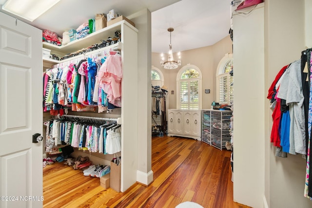 walk in closet featuring wood-type flooring and a chandelier