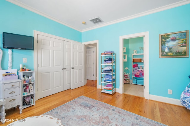 bedroom featuring crown molding, connected bathroom, hardwood / wood-style floors, and a closet