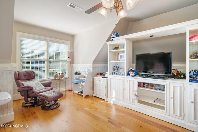 living area with light hardwood / wood-style flooring, ceiling fan, and vaulted ceiling