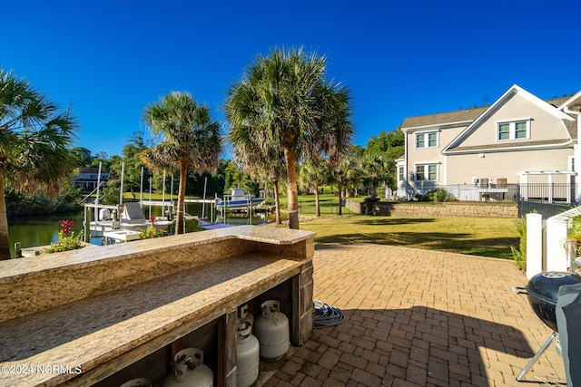 view of patio featuring a water view, a grill, and a dock