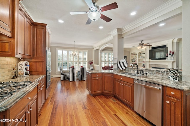 kitchen featuring appliances with stainless steel finishes, sink, pendant lighting, and light stone counters