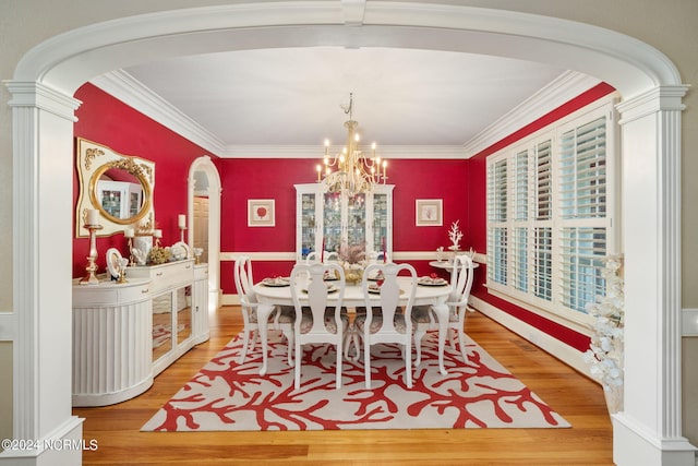 dining space with crown molding, wood-type flooring, decorative columns, and a notable chandelier