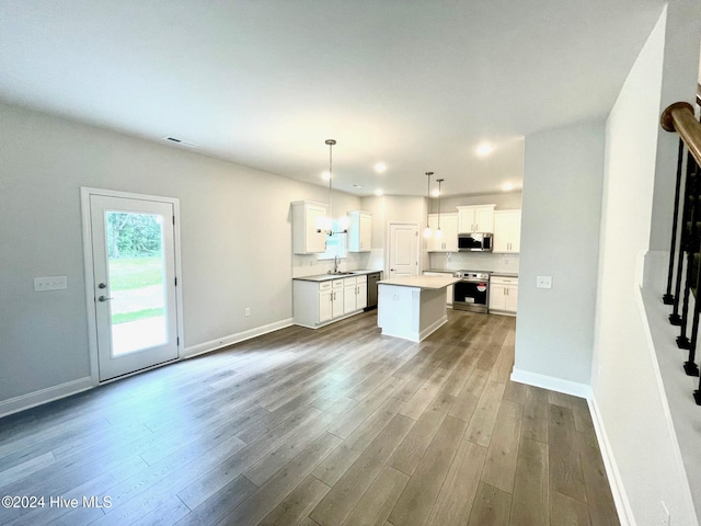 kitchen with a center island, pendant lighting, stainless steel appliances, light countertops, and white cabinetry