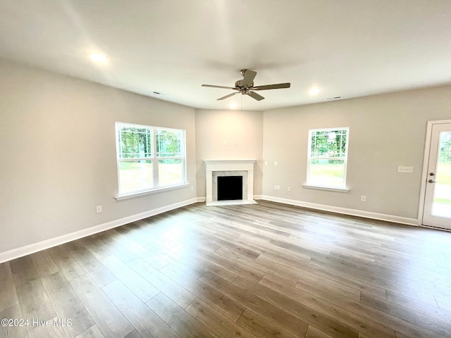 unfurnished living room with a fireplace with flush hearth, a healthy amount of sunlight, baseboards, and wood finished floors