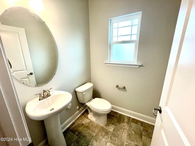 half bathroom with toilet and baseboards