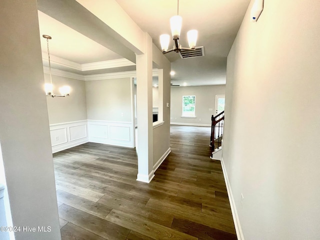 hallway featuring a chandelier, a decorative wall, visible vents, stairway, and dark wood finished floors