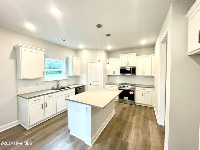 kitchen with appliances with stainless steel finishes, a center island, white cabinetry, and a sink