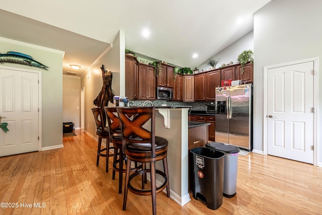 220 Everett Yopp Dr, Sneads Ferry, NC 28460 - kitchen with appliances with stainless steel finishes, dark countertops, a breakfast bar, tasteful backsplash, and a peninsula