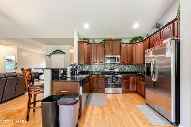 220 Everett Yopp Dr, Sneads Ferry, NC 28460 - kitchen with stainless steel appliances, open floor plan, light wood-style floors, a kitchen bar, and tasteful backsplash