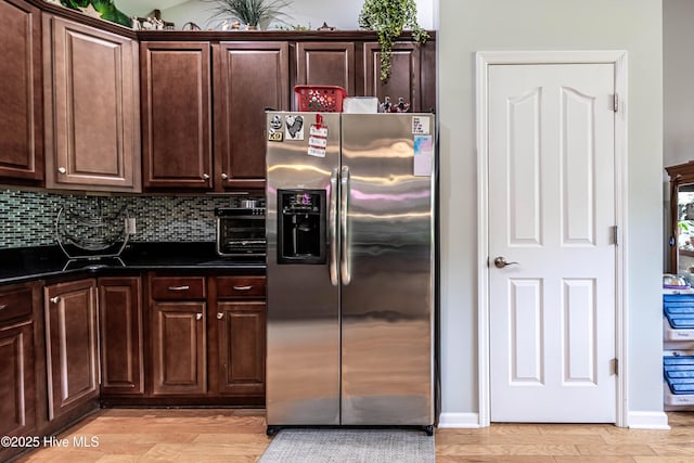 220 Everett Yopp Dr, Sneads Ferry, NC 28460 - kitchen with stainless steel refrigerator with ice dispenser, dark countertops, dark brown cabinets, light wood-type flooring, and backsplash