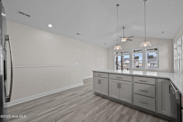 kitchen with appliances with stainless steel finishes, gray cabinetry, pendant lighting, light hardwood / wood-style flooring, and lofted ceiling