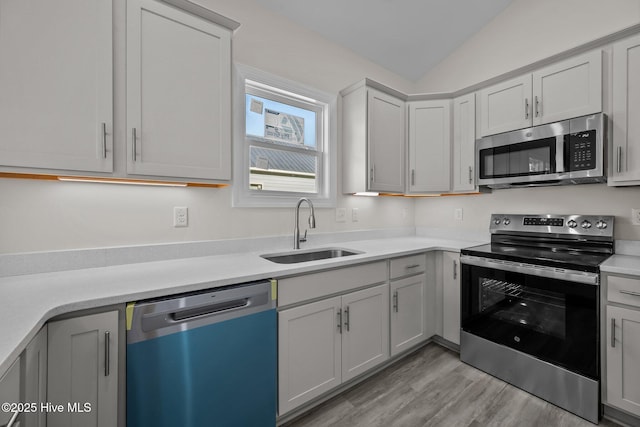 kitchen featuring sink, lofted ceiling, light hardwood / wood-style floors, and appliances with stainless steel finishes