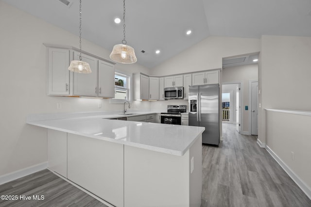 kitchen featuring sink, stainless steel appliances, kitchen peninsula, and hanging light fixtures