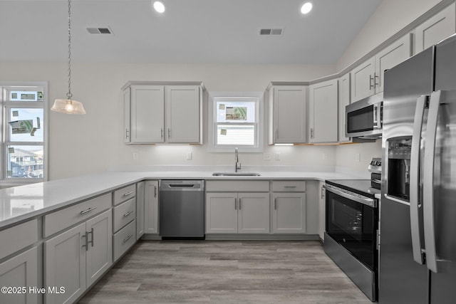 kitchen featuring appliances with stainless steel finishes, decorative light fixtures, gray cabinets, and sink