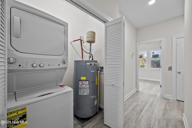 laundry room with stacked washer and clothes dryer, light wood-type flooring, and electric water heater