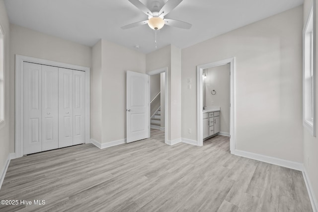 unfurnished bedroom with ceiling fan, light wood-type flooring, ensuite bathroom, and a closet