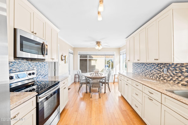 27 Newport St, Ocean Isle Beach, NC 28469 - kitchen with appliances with stainless steel finishes, light wood-style flooring, decorative backsplash, ornamental molding, and white cabinets