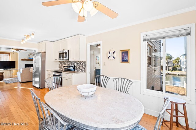 27 Newport St, Ocean Isle Beach, NC 28469 - dining area featuring ceiling fan, crown molding, plenty of natural light, light wood finished floors, and a wainscoted wall