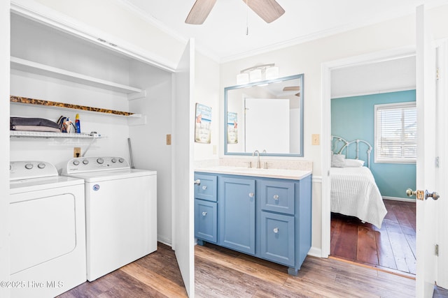 laundry area featuring sink, ceiling fan, washing machine and dryer, crown molding, and dark wood-type flooring