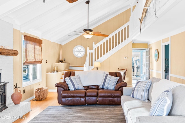 living room with wood walls, ceiling fan, hardwood / wood-style flooring, and a wood stove