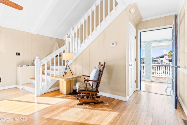 staircase featuring wooden walls, vaulted ceiling with beams, and wood-type flooring