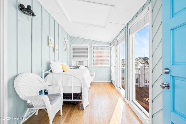 bedroom with light hardwood / wood-style flooring, cooling unit, vaulted ceiling, and wood walls