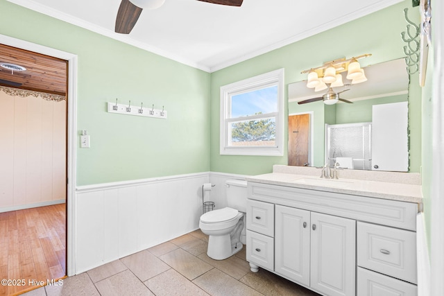 27 Newport St, Ocean Isle Beach, NC 28469 - bathroom featuring a ceiling fan, vanity, ornamental molding, toilet, and a wainscoted wall