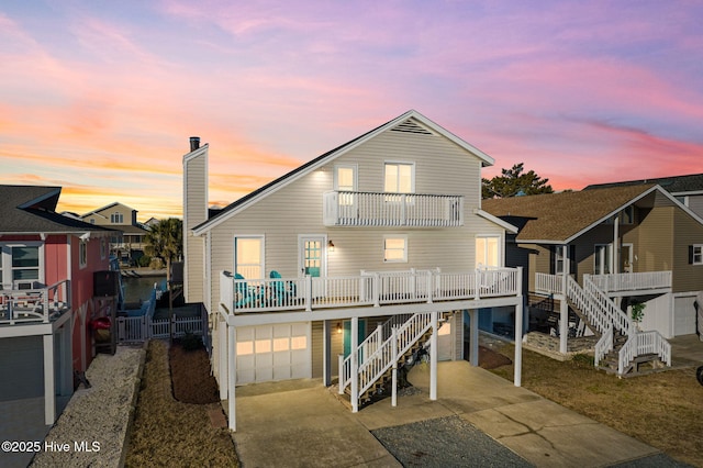 27 Newport St, Ocean Isle Beach, NC 28469 - back of house at dusk with a balcony, stairs, a garage, and driveway