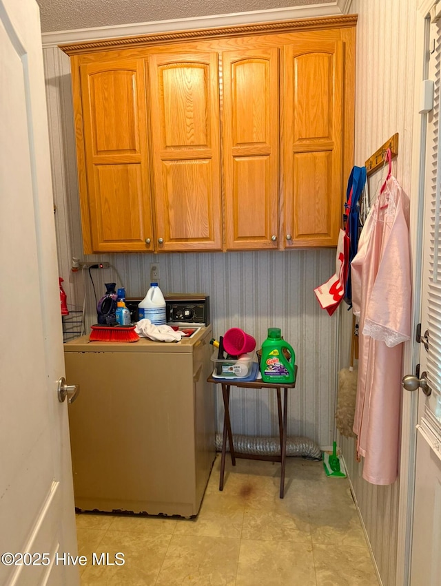 laundry area featuring wallpapered walls, washer / clothes dryer, and cabinet space