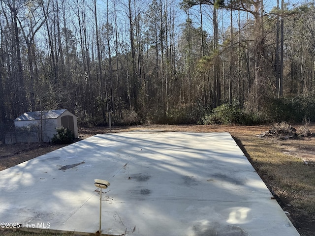 view of patio with a storage unit, an outbuilding, and a wooded view