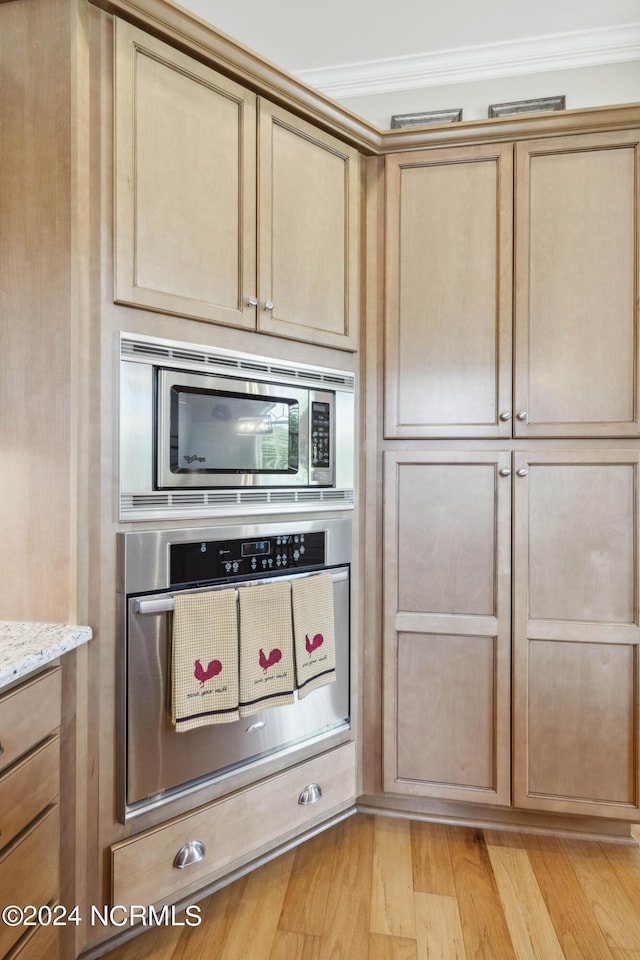 kitchen featuring stainless steel appliances, light stone counters, crown molding, and light hardwood / wood-style floors