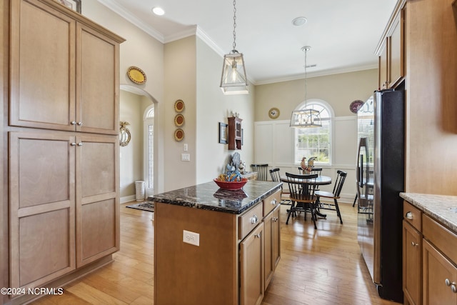 kitchen featuring a center island, dark stone countertops, decorative light fixtures, light hardwood / wood-style floors, and stainless steel refrigerator