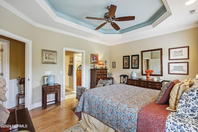 bedroom with ceiling fan, ensuite bathroom, crown molding, and a tray ceiling