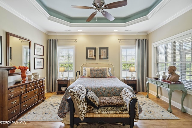 bedroom featuring light hardwood / wood-style floors, a raised ceiling, ceiling fan, and ornamental molding