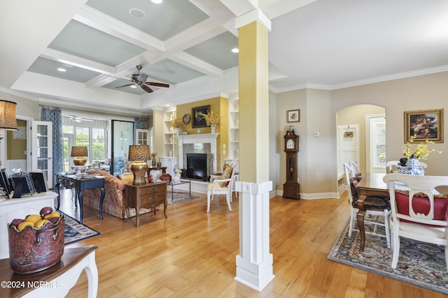 living room with beam ceiling, ceiling fan, coffered ceiling, decorative columns, and light wood-type flooring