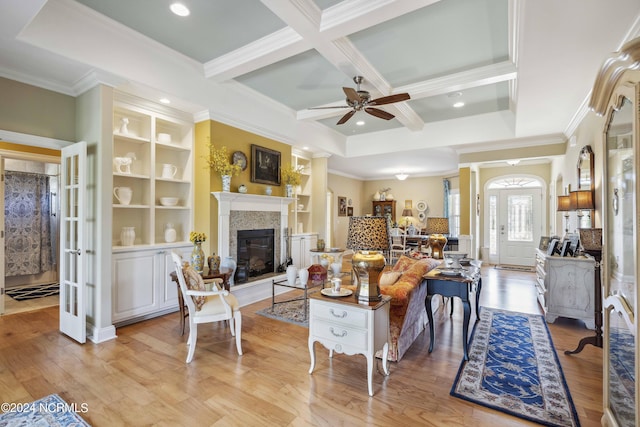 living room with coffered ceiling, built in shelves, ceiling fan, light hardwood / wood-style flooring, and beamed ceiling