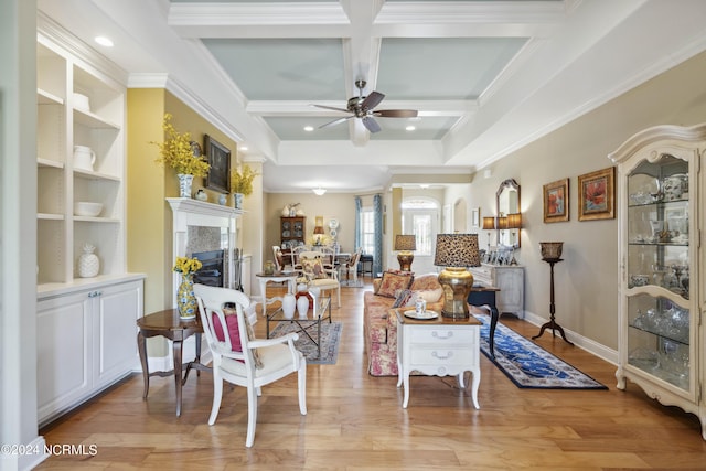 living room with beam ceiling, ceiling fan, coffered ceiling, light wood-type flooring, and ornamental molding