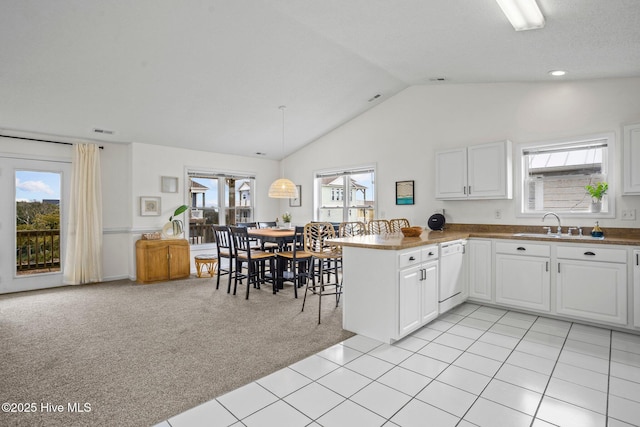 kitchen featuring light carpet, kitchen peninsula, dishwasher, white cabinetry, and plenty of natural light