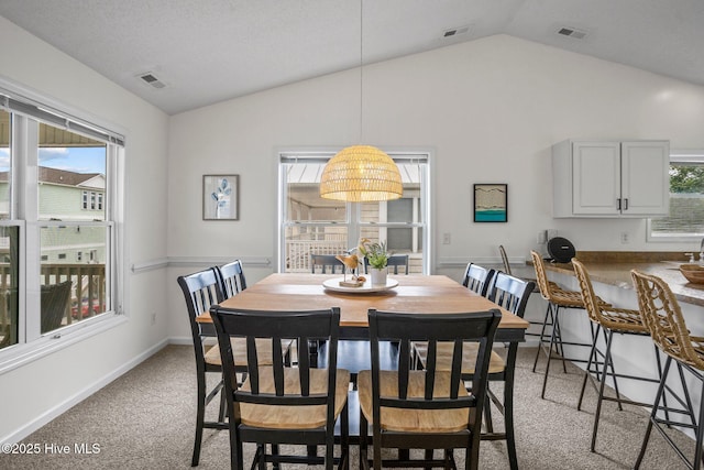 dining space featuring light colored carpet and lofted ceiling