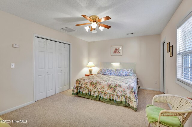 carpeted bedroom featuring ceiling fan, ensuite bath, a closet, and a textured ceiling