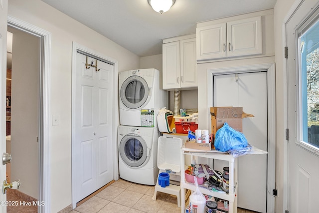 laundry area featuring cabinet space, stacked washer and dryer, and light tile patterned flooring