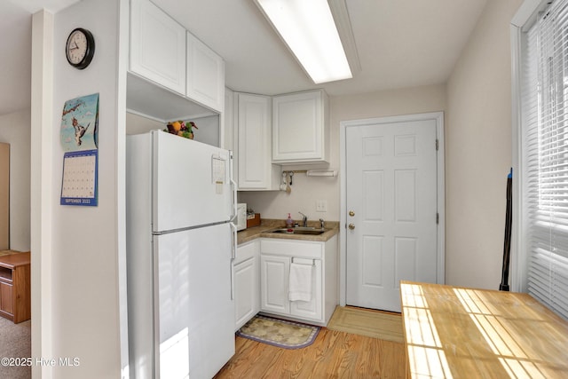 kitchen with sink, white refrigerator, white cabinetry, and light hardwood / wood-style floors