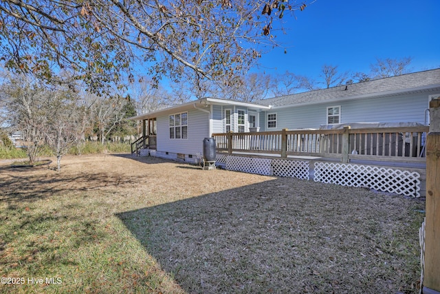 rear view of property featuring crawl space, a wooden deck, and a yard