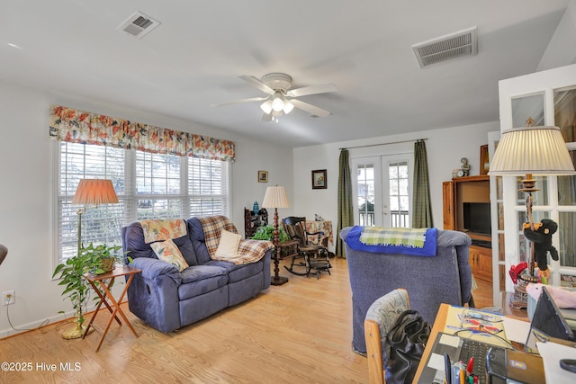 living room with ceiling fan, french doors, a wealth of natural light, and light hardwood / wood-style floors