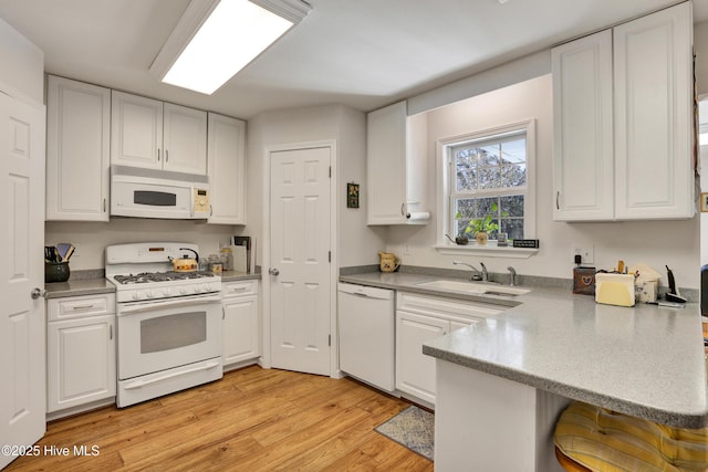 kitchen featuring kitchen peninsula, sink, white appliances, and white cabinetry