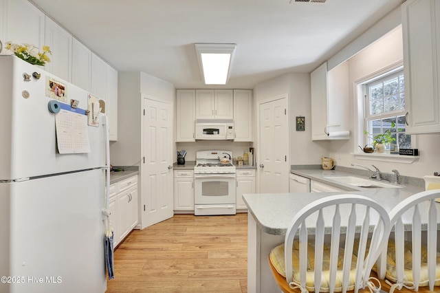 kitchen featuring light wood-type flooring, a peninsula, white appliances, white cabinetry, and a sink