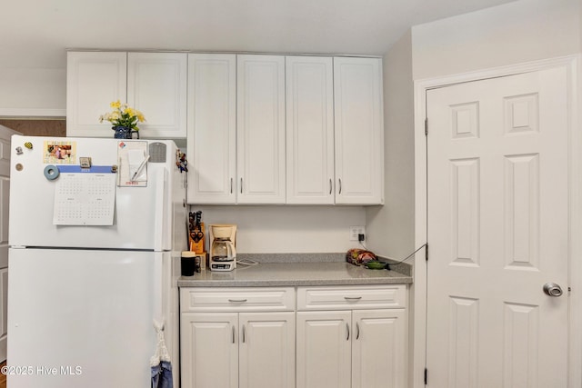 kitchen featuring white cabinetry, light countertops, and freestanding refrigerator