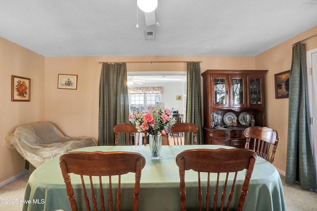 dining space featuring ceiling fan, light colored carpet, and a textured ceiling