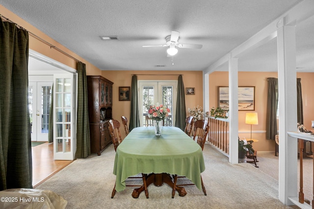 dining room featuring visible vents, light colored carpet, french doors, a textured ceiling, and a ceiling fan