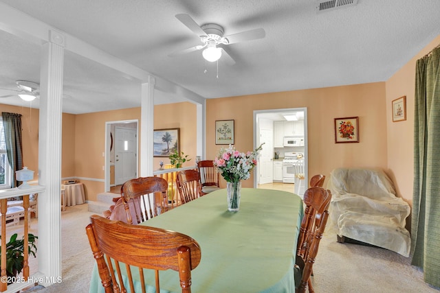 dining space with visible vents, light carpet, a textured ceiling, and a ceiling fan